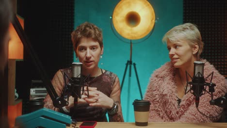 female fashion influencers giving interview to podcast host in studio