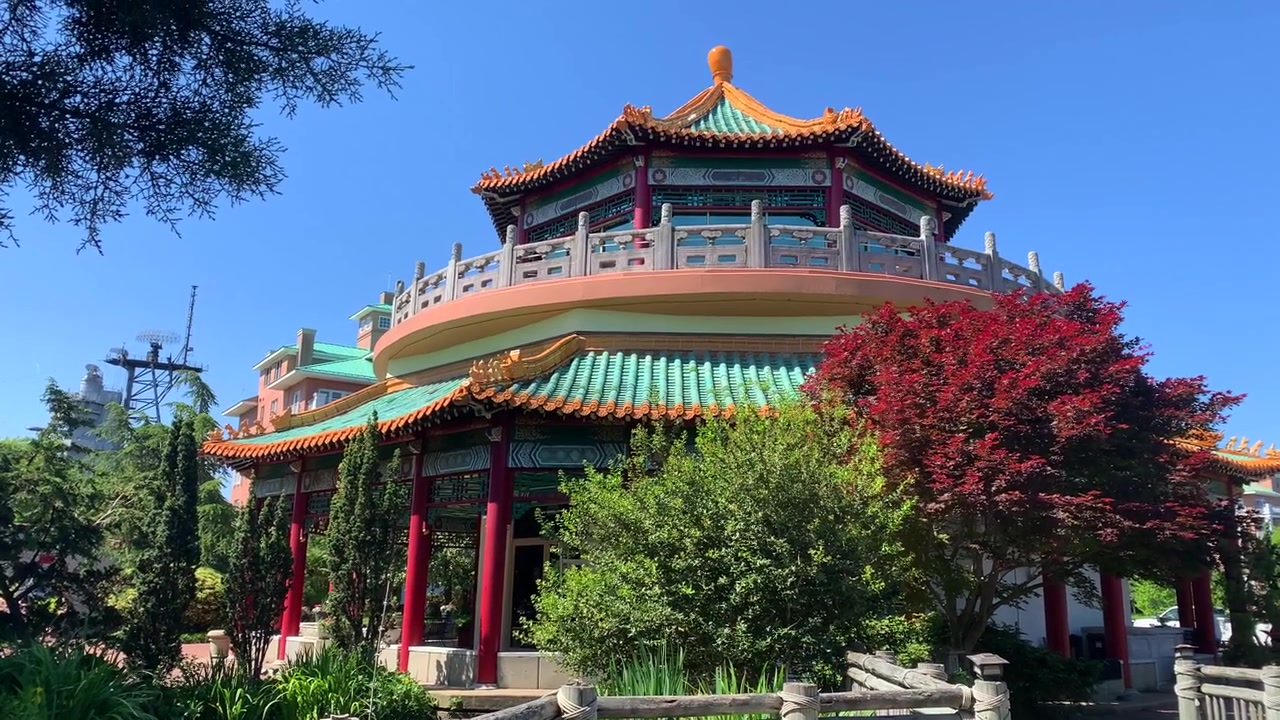 Taiwansk vennskapspaviljong i Norfolk, VA. Fargerike arkitektoniske detaljer mot blå himmel. Panorering fra hage og fontene til toppen av den utsmykkede bygningen.