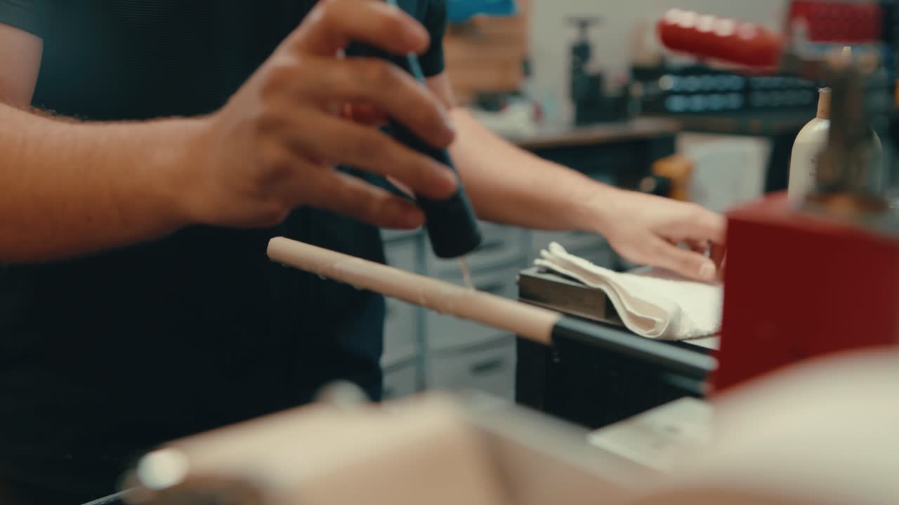 カウカシアの男性の手はスローモーションでゴルフクラブのシャフトに落ちる水を注ぎカスタムに合わせたゴルフアイロンを準備しています