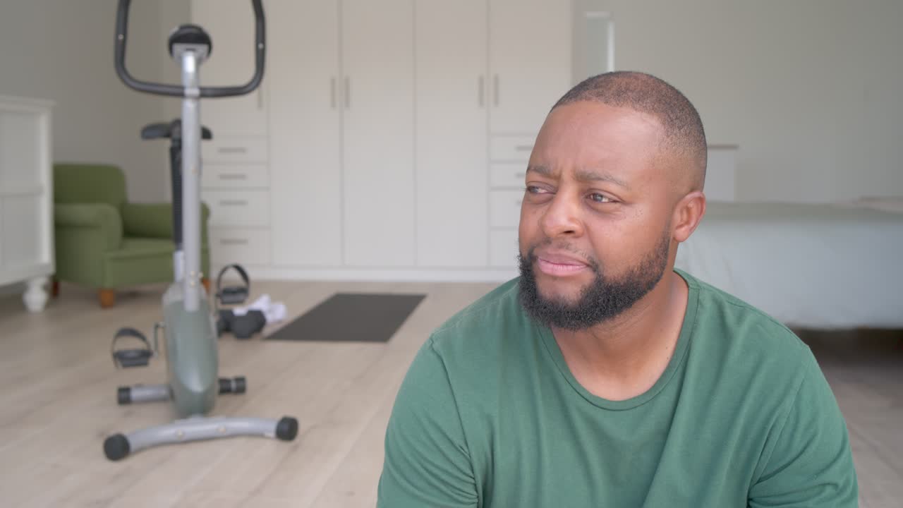 African American man shifting gaze after offscreen cue, smiling and laughing on floor near bike