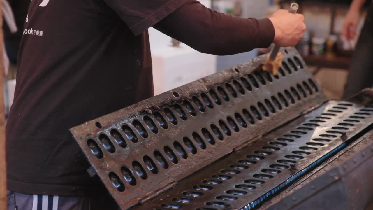 Iron skillet oiled with brush to prepare for egg waffle batter to be poured in