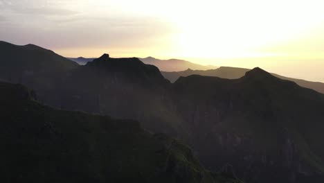 Aerial-View-of-Madeira-Island-Countryside-Landscape-at-Sunset,-Silhouettes-of-Mountain-Peaks-and-Sunny-Horizon,-Drone-Shot