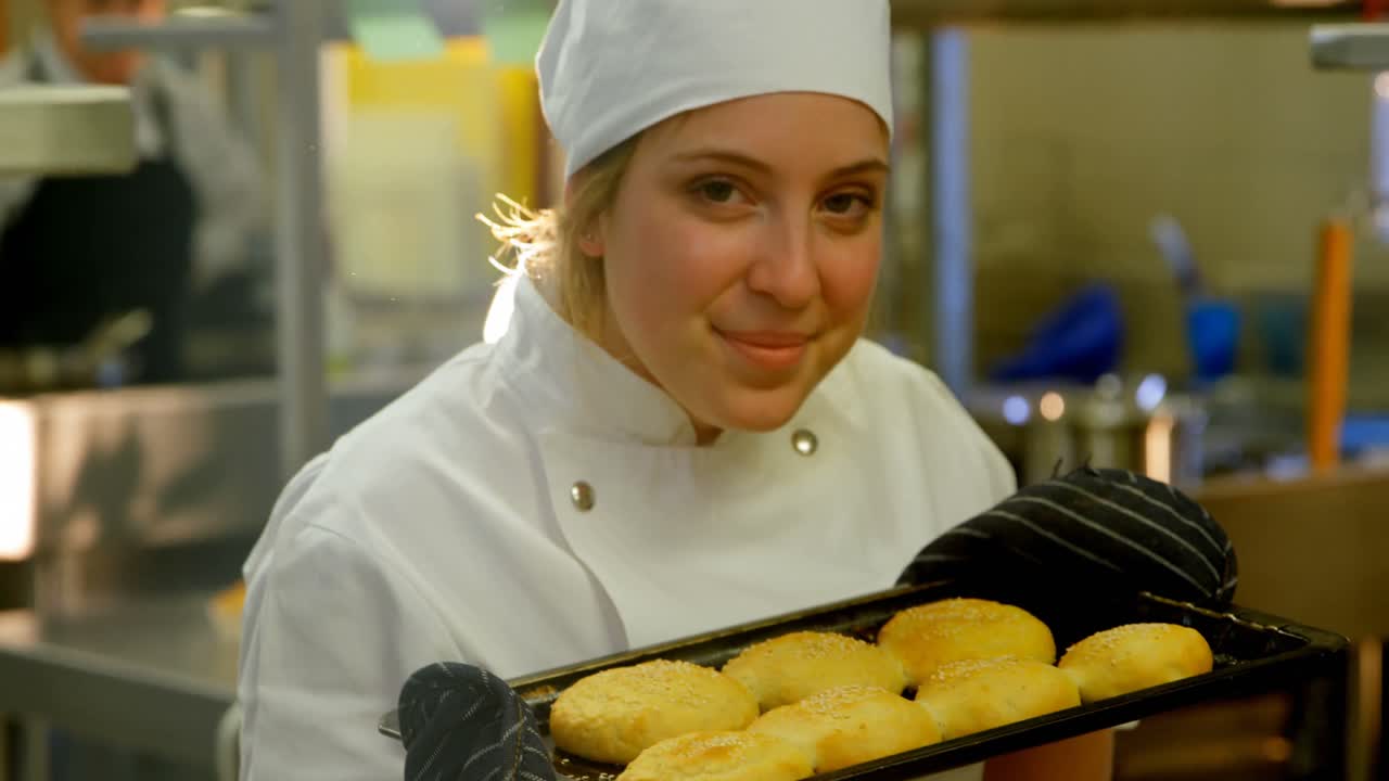 Chef feminina segurando bandeja de biscoitos na cozinha 4k