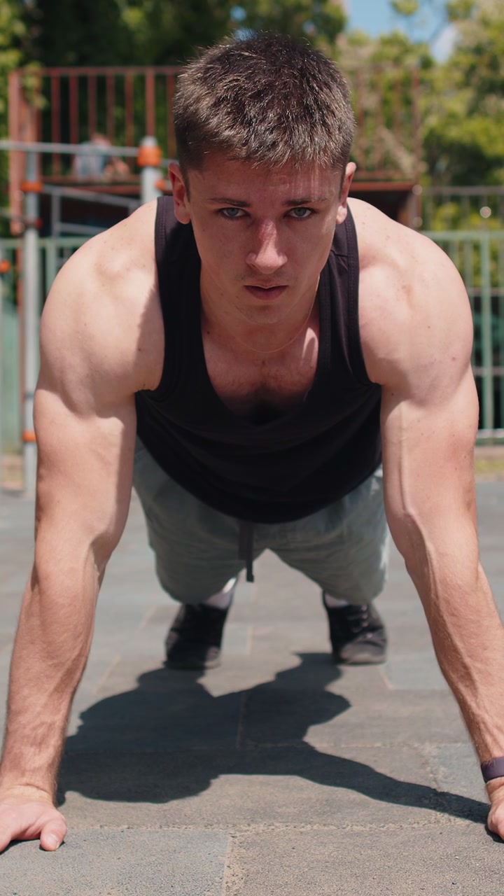 Uomo bodybuilder atletico caucasico in abbigliamento sportivo che esegue un allenamento di flessioni a terra.
