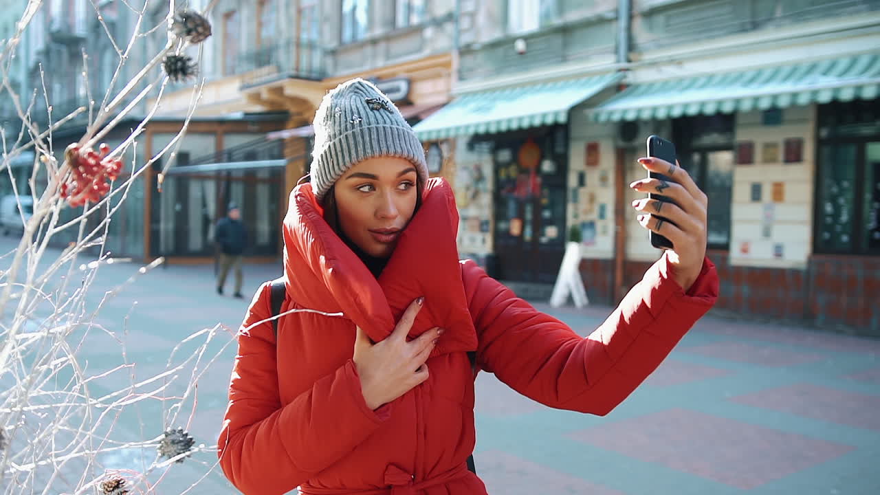 Woman taking selfie on a city street in winter