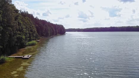 luftaufnahmen von drohnen über einem see und neben einem wald in borowy młyn, pomeranien, polen