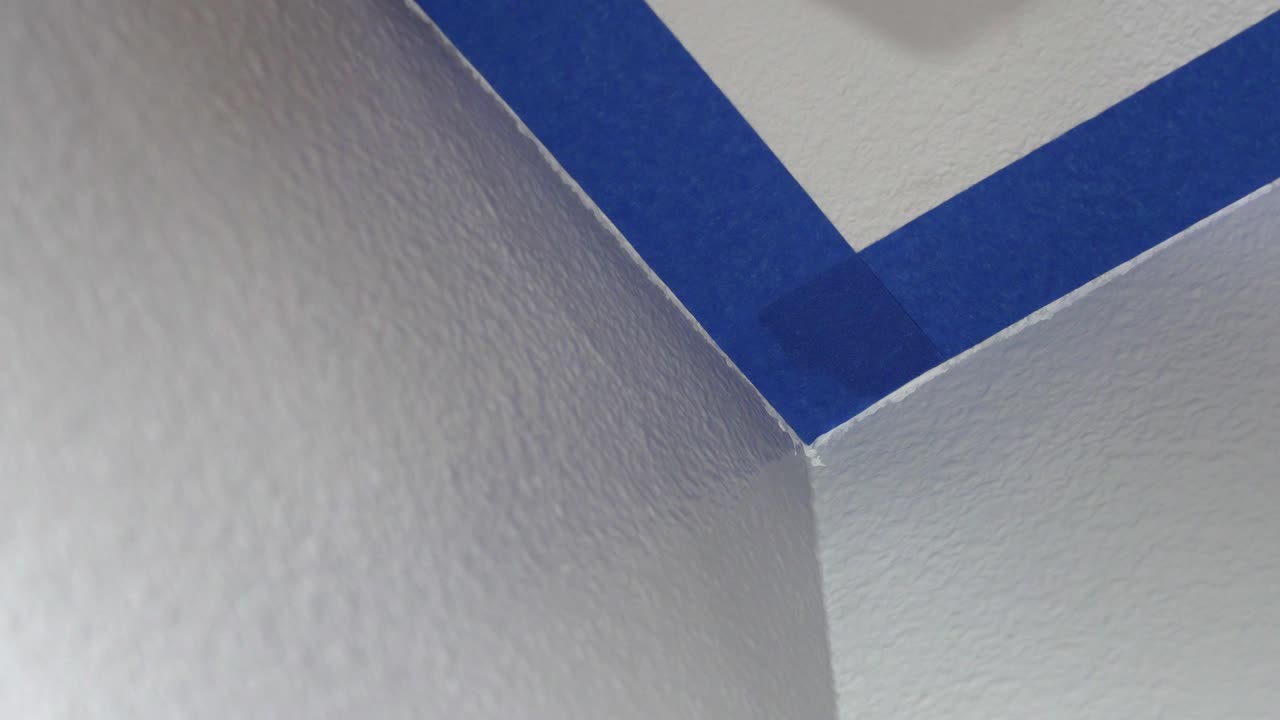 4k, pintor usando cinta azul de enmascaramiento para asegurar el techo. preparación para la pintura de la habitación.