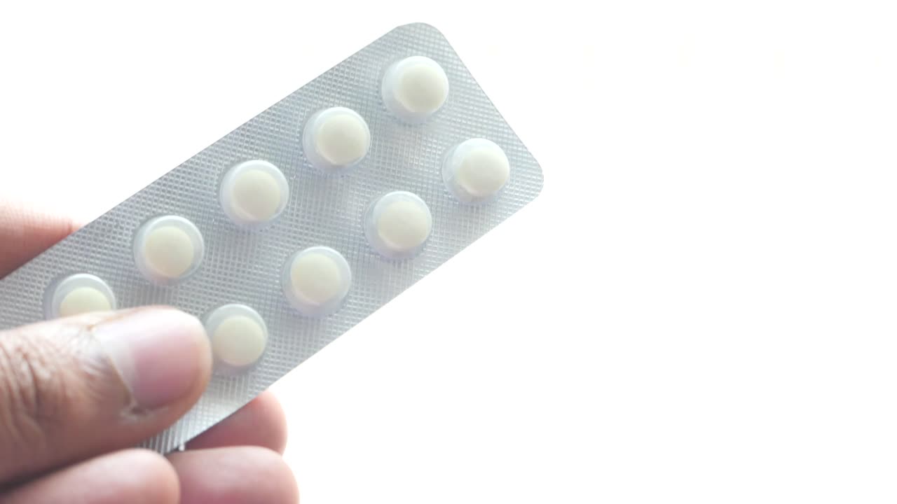 mano con un paquete de pastillas blancas