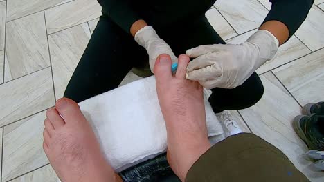 pov, female pedicurist toe separator the man's right and left foot