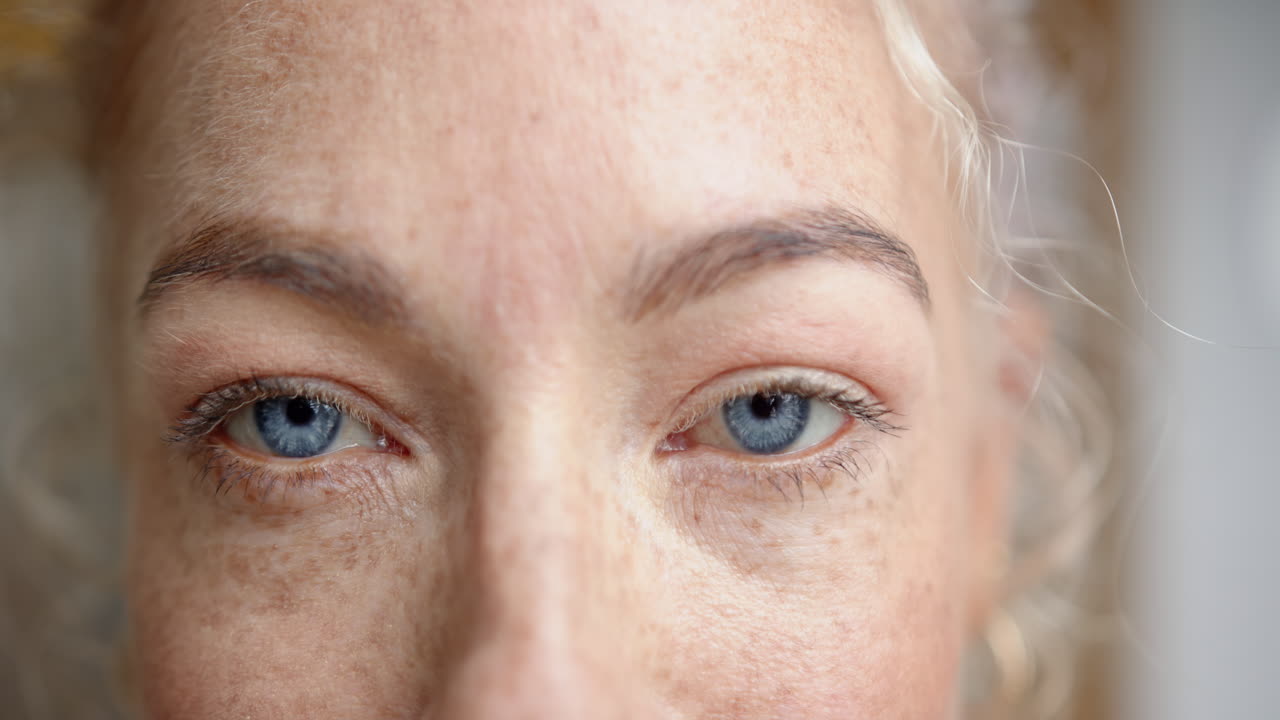 Close-up of woman's blue eyes and freckles, showing natural beauty and detail