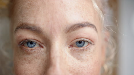 close-up of woman's blue eyes and freckles, showing natural beauty and detail