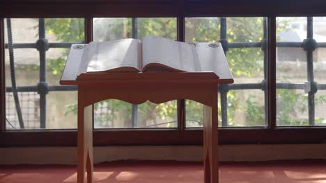 open book on wooden stand by window