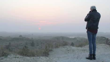 wide shot of a landscape photographer man taking photos in nature at sunset or sunrise