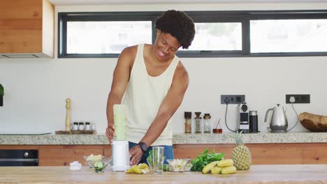 fit african american man cooking, preparing healthy green smoothie