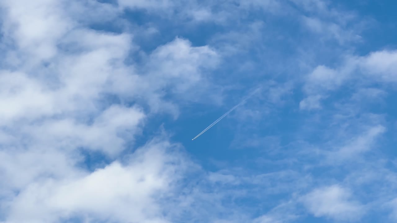 A fast airplane crosses the blue sky leaving a white contrail — symbol of travel, technology, and speed