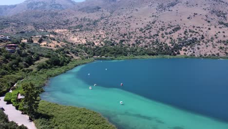 hermoso lago kournas en creta con botes en el agua turquesa que revela las montañas y el cielo azul