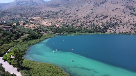 beautiful kournas lake in crete with boats on the turquoise water revealing the mountains and blue sky