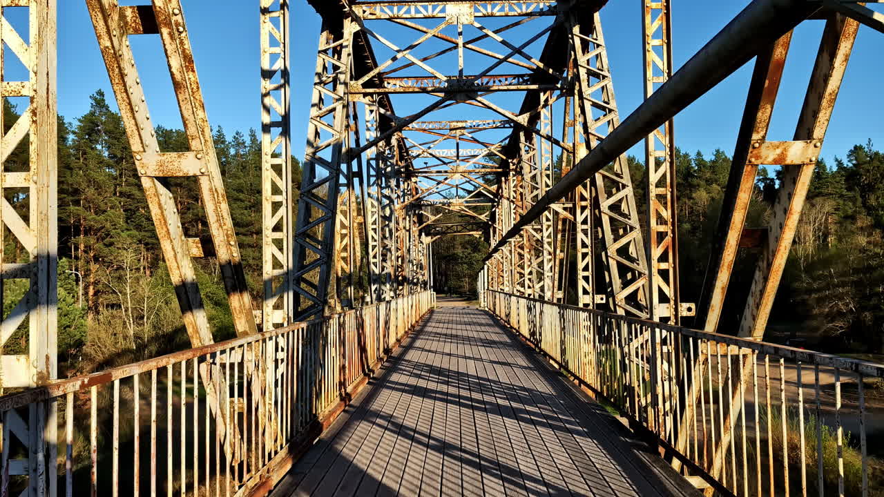 Old rusty metal bridge over river with golden hour sunlight