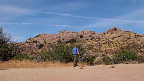 hombre caucásico caminas en el desierto suroeste, california cerca de formaciones rocosas