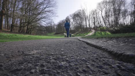 Man-drives-a-witty-radio-controlled-car-behind-walking-woman-in-beautiful-Woluwepark-in-wide-angle