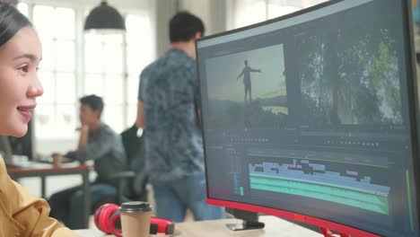 asian female video editor works with footage and sound on her personal computer in office