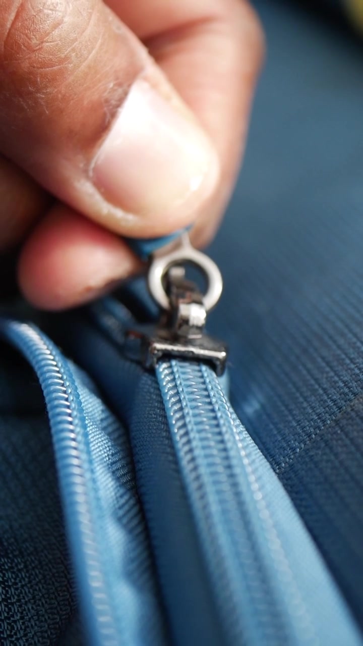 Close-up de uma Mão Fechando o Zíper de uma Mala Azul