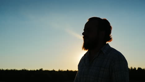 silhouette of a bearded man who smokes at sunset