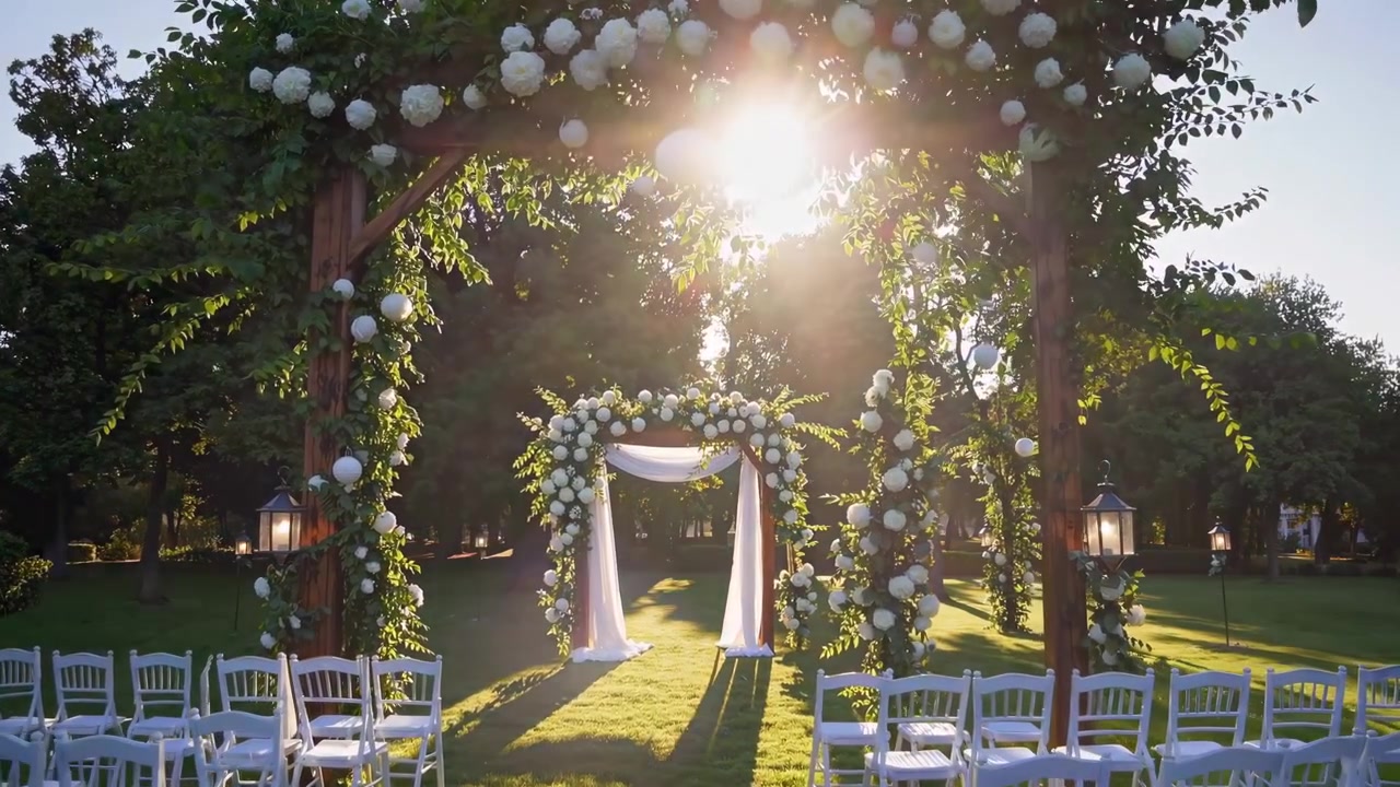 Allestimento per cerimonia di matrimonio all'aperto con arco floreale al tramonto.