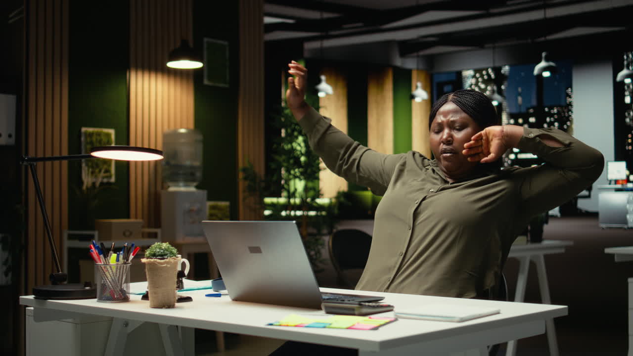 Female office worker managing daily tasks at night with focus music on headset