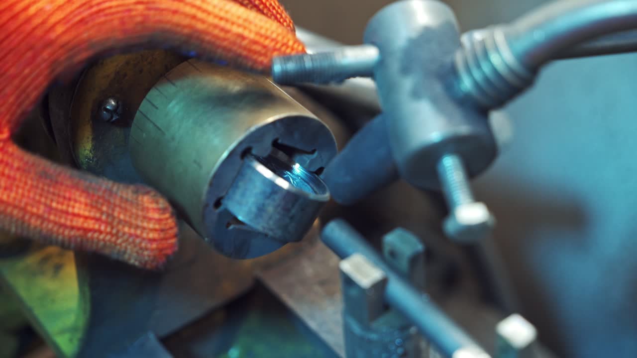 Professional machinist puts metal instruments to the machine. Man's hands operating lathe grinding machine metalworking industry concept. Close-up