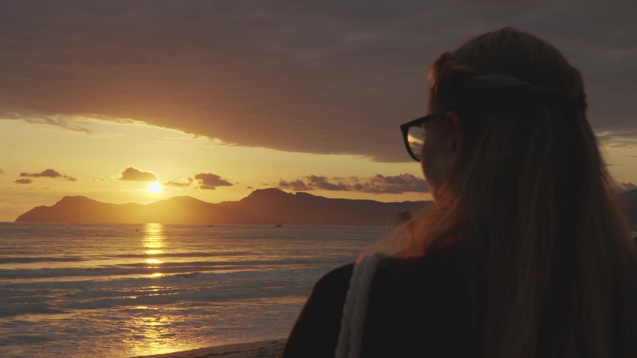 Una donna si gode la vista del mare all'alba.