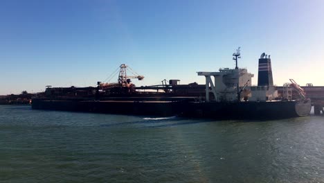 a static shot of huge cargo ship carrying huge truck size containers cruising deep blue sea