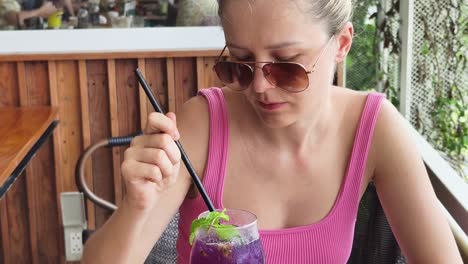 mujer disfrutando de una bebida púrpura en un café al aire libre