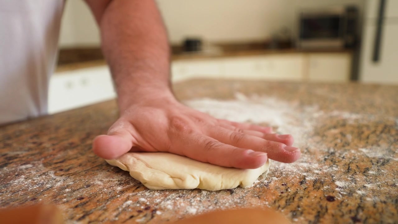 Chef che prepara impasto fresco per pizza, trasformandolo in una crosta perfetta pronta per i condimenti.