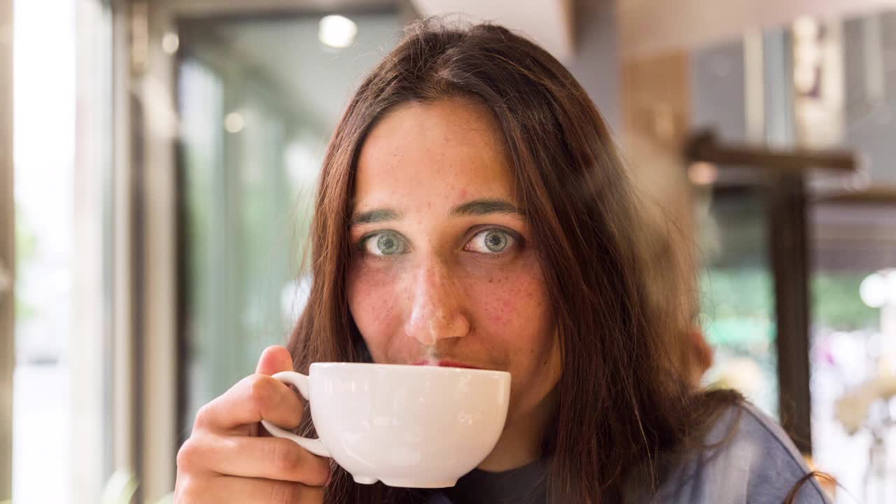 joven con una taza de café humeante mirando a la cámara