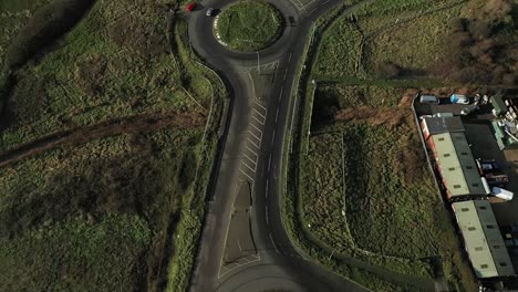 Aerial-:-Pan-up-from-ground-to-roundabout-as-cars-enter-and-exit