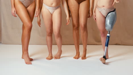 group of diverse women body positive friends one with prosthetic limb in underwear with crossed arms