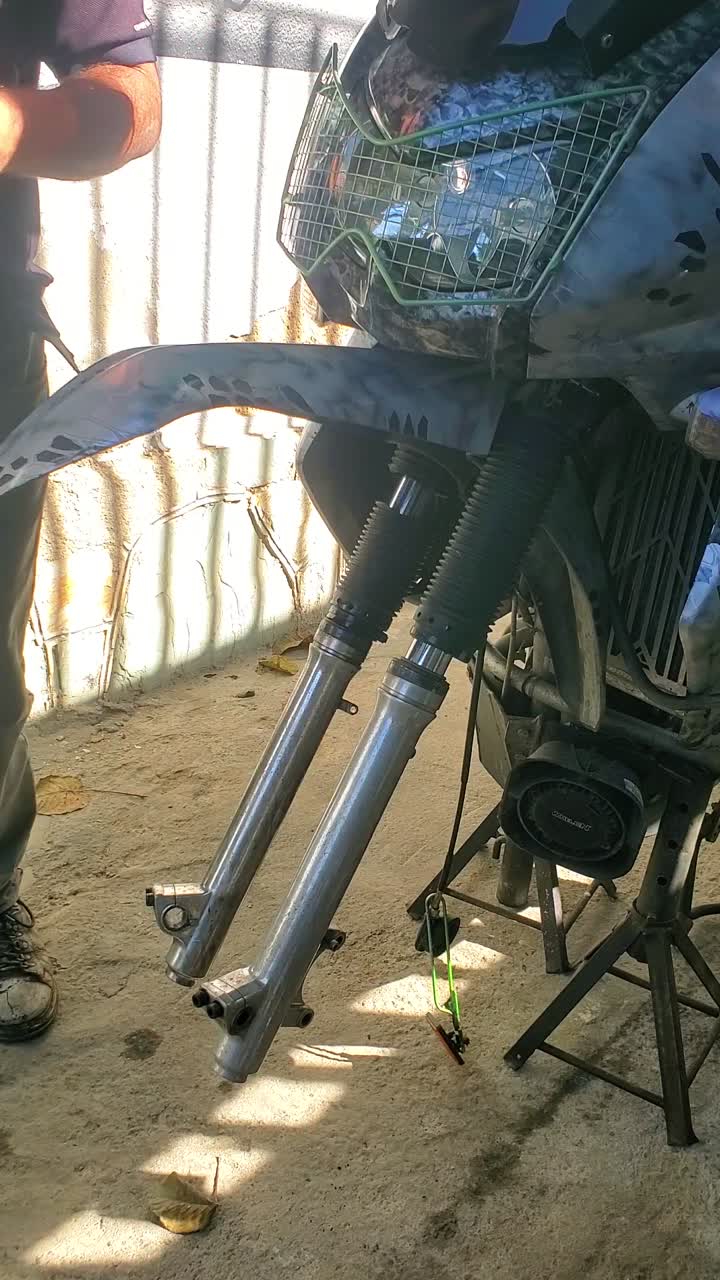 Mechanic adjusting motorcycle front fork and fender with camo paint and protective gloves during maintenance