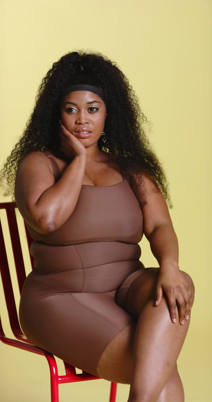 Video verticale: Donna afroamericana che si acconcia i ricci e mostra gli orecchini su una sedia rossa in studio.