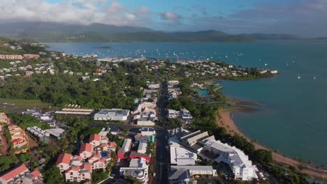 Airlie-Beach-Bay-Lagoon-heart-of-Great-Barrier-Reef-Whitsundays-Whitehaven-aerial-drone-main-street-cars-buildings-sunrise-morning-mist-sunny-Coral-Sea-marina-jetty-sailboats-backwards-motion