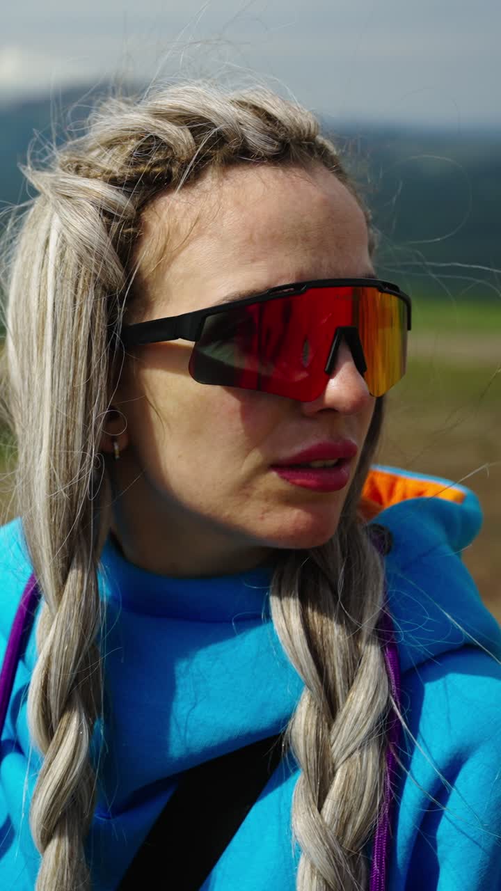 Young Woman with Braids and Sunglasses Looking at Mountain Landscape