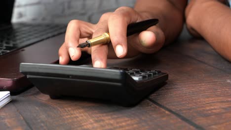 person using a calculator and fountain pen at a desk