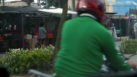 slow motion street view of street vendors, masked people, vehicles, motorcycles driving by in zone 18 guatemala city, guatemala