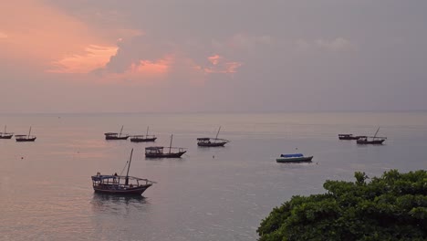 Zanzibar-Indian-Ocean-Sunset-with-Boats-in-Tanzania,-Africa,-Red-and-Orange-African-Sunset-Scenery-on-the-Coast-in-Stone-Town-Harbour-and-Port-with-Views-Out-to-Sea-and-the-Horizon-with-a-Sunset-Sky