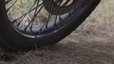 close up on motorcycle wheels, static on soil ground, low ground view pan movement 120fps