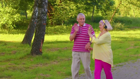 Senior-stylish-couple-family-grandmother-grandfather-dancing,-walking-listening-music-in-summer-park