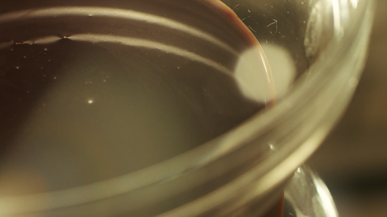 Primo piano di un pasticcere che mescola cioccolato liquido con un mixer al rallentatore.