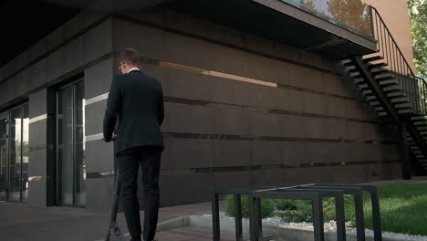 businessman riding electric scooter outside modern office building