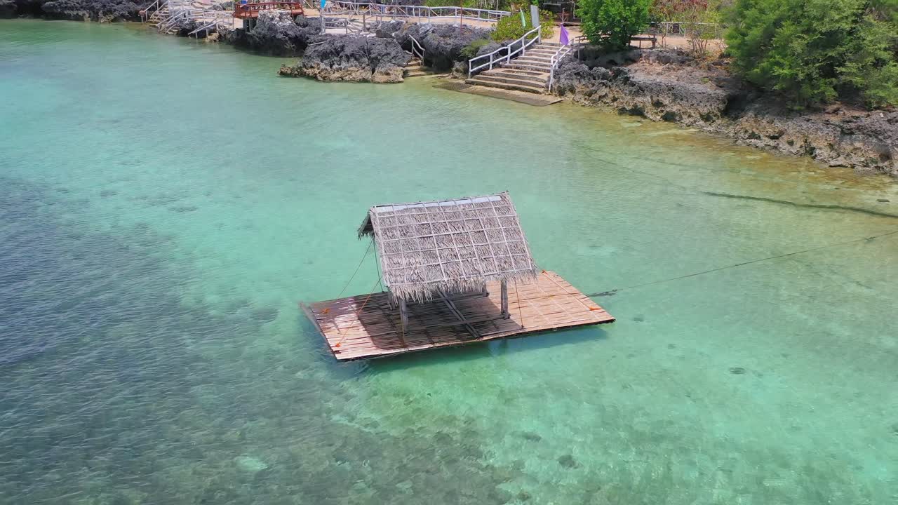 Floating raft in clear shallow water by seashore, Philippines, circle aerial