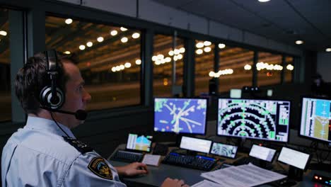 aerial view of an air traffic controller in a dimly lit tower, monitoring multiple screens